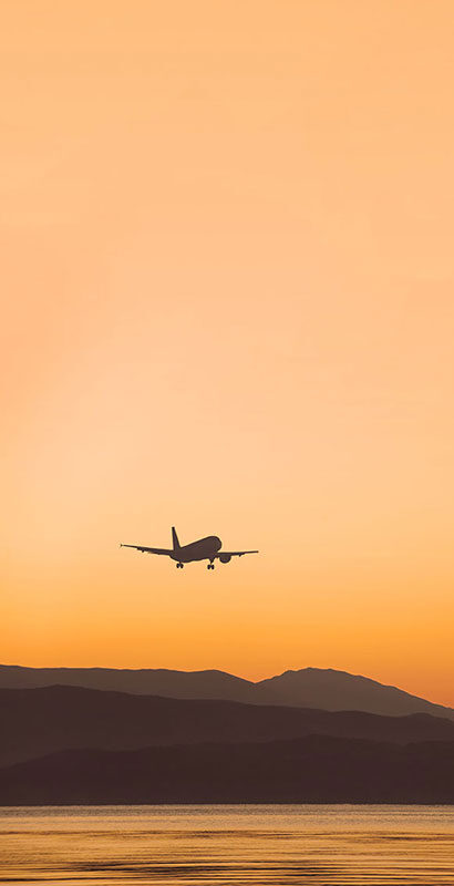 Plane flying over a lake at sunset